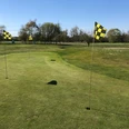 Golfplatz Rehburg-Loccum Aussicht auf einen gepflegten, weitläufigen Golfplatz mit Fahnen, umgeben von Bäumen und blauem Himmel.