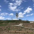 Aussichtsplattform Leese Eine runde Aussichtsplattform mit Geländer und Baum in zentraler Position vor blauem Himmel mit Wolken.