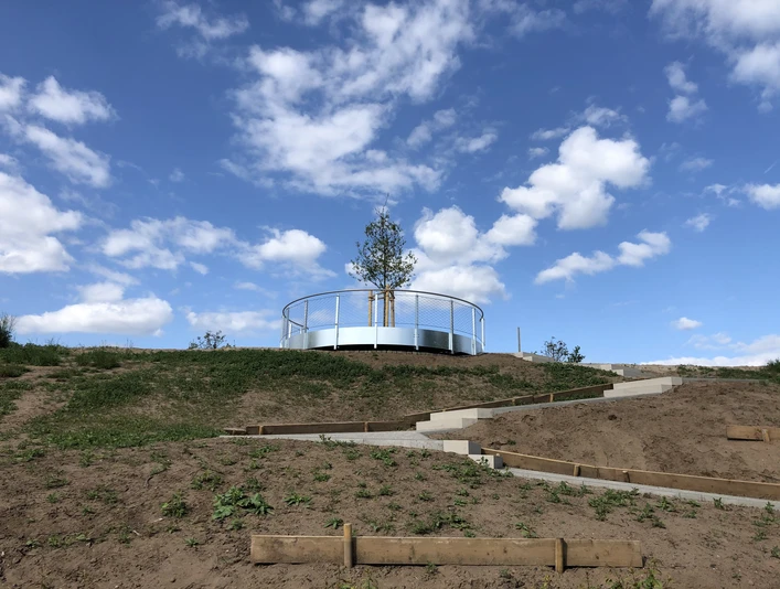Aussichtsplattform Leese Eine runde Aussichtsplattform mit Geländer und Baum in zentraler Position vor blauem Himmel mit Wolken.
