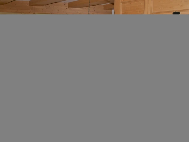 Da Nico in Farchant - Innenbereich Ein Holztresen mit der Kasse, Notizbuch und Ölflaschen im Vordergrund, etwas weiter hinten ein Holzregal mit Weinflaschen