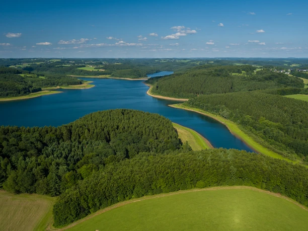 Große Dhünn- Talsperre <p>Luftaufnahme einer bewaldeten Halbinsel, umgeben von einem blau schimmernden See unter klarem Himmel.</p>