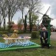 Lieblingsort Freibad Hengstforde Ein Mann kniet neben einem Hund vor einem dekorativen, mosaikartigen Aufsteller, im Hintergrund eine Windmühle.