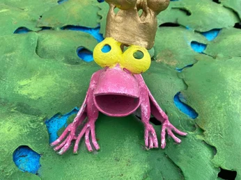 Frosch im Lieblingsort Die Froschfigur spiegelt humorvoll die Märchenwelt wider, die zum Träumen einlädt. Auf einer dekorativ gestalteten Oberfläche positioniert, erweckt dieser charmante Frosch mit seiner auffälligen, golden bemalten Krone lebhafte Bilder von fabelhaften Abenteuern. Die leuchtend pinke Farbe und die überdimensionalen Augen verleihen ihm eine verspielte Ausstrahlung, die sowohl Kinder als auch Erwachsene zum Schmunzeln bringt. Diese Kreation lädt Besucher ein, ihrer Fantasie freien Lauf zu lassen, während sie das kunstvolle Zusammenspiel von Farben und Formen bewundern. Ein wahrer Blickfang, der die Umgebung mit einem Hauch von Märchenzauber bereichert.