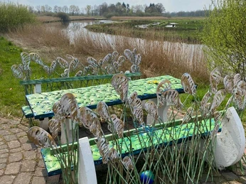 Lieblingsort alte Staaßen Brücke Eine kunstvoll gestaltete Sitzgruppe mit filigranen Grashalmen säumt das Ufer eines beschaulichen Flusses.