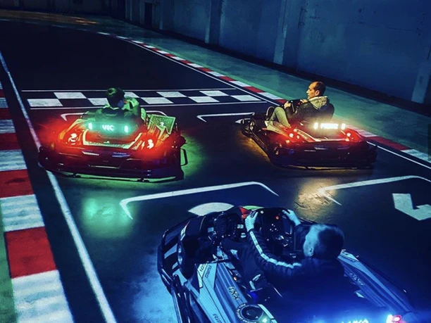 Startaufstellung II.jpg Beim nächtlichen Go-Kart-Fahren sind drei Fahrer in leuchtenden Karts bei einem spannenden Rennen zu sehen.