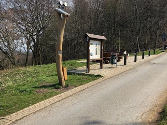 Hörstele Kumsttonne Oerlinghausen Eine Hörstation neben einem Weg im Freien, umgeben von Bäumen und einer Infotafel.