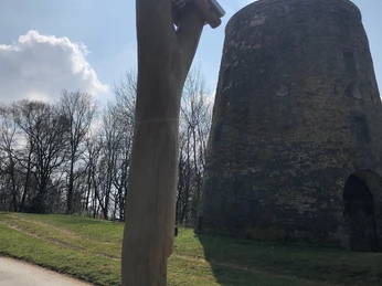 Hörstele Kumsttonne Oerlinghausen Holzstele mit Lautsprechern vor einem alten steinernen Rundturm, umgeben von naturreicher Umgebung.
