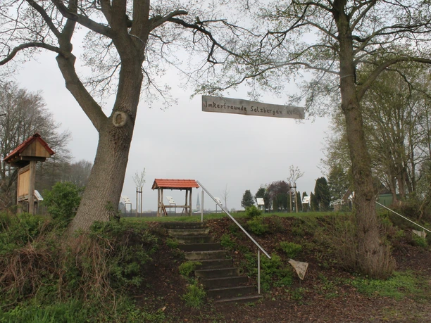 Bienenlehrpfad in Salzbergen (Am Emsradweg) Holztafeln und kleine Pavillons des Bienenlehrpfads Salzbergen zwischen Bäumen und Wiesenlandschaft.