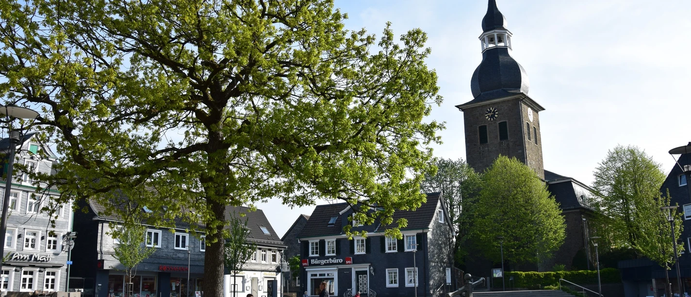 Marktplatz <p>Ein Baum und eine Kirche prägen den Marktplatz mit historischen Fachwerkhäusern in Radevormwald.</p>