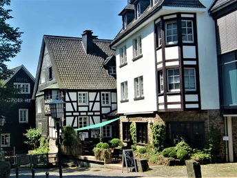 Ortskern Nümbrecht <p>Historische Fachwerkhäuser in einer sonnigen Gasse in Nümbrecht, umgeben von Grün.</p>