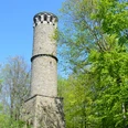 Kahlenbergturm Runder steinerner Aussichtsturm im Kahlenbergwald, von üppigem Frühlingslaub umgeben, bei klarem Himmel.