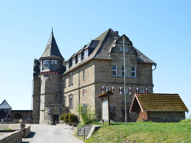 Historische Burg Schwalenberg mit markantem Turm, umgeben von Natur und klarem Himmel.