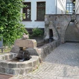 Volkwinbrunnen Ein steinerner Brunnen mit Wasserbecken und Relief, umgeben von gepflastertem Hof und Fachwerkhäusern.