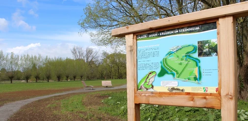 Infoschild Emmerauen Weg Infoschild zum Emmerauen Weg mit Karte, Beschreibung und Bildern in einer grünen Parklandschaft.