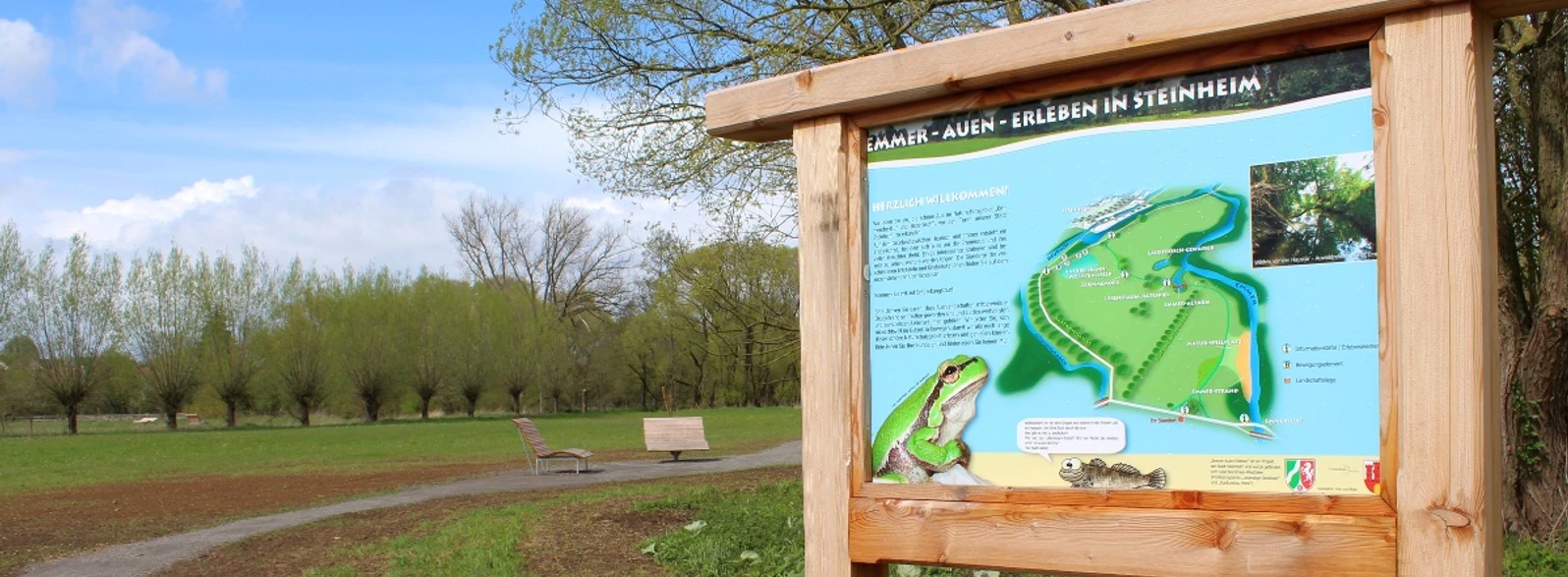 Infoschild Emmerauen Weg Infoschild zum Emmerauen Weg mit Karte, Beschreibung und Bildern in einer grünen Parklandschaft.
