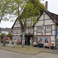 Teddy- und Puppenmuseum Fachwerkhaus mit bunten Puppen und Teddybären, umgeben von Bäumen und einer ruhigen Straße.