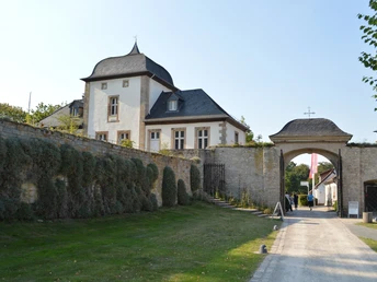 Kloster Dalheim Ehemaliges Kloster Dalheim mit historischem Torbogen und umliegendem Park bei hellem Tageslicht.