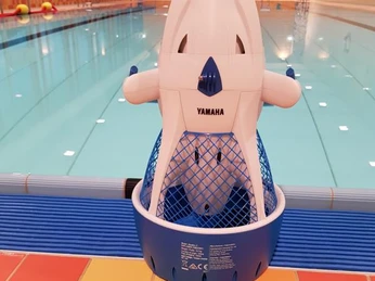 Bröltal-Bad Seascooter.jpg Ein Schwimmroboter der Marke Yamaha steht am Beckenrand in einem Hallenbad mit klarem Wasser.