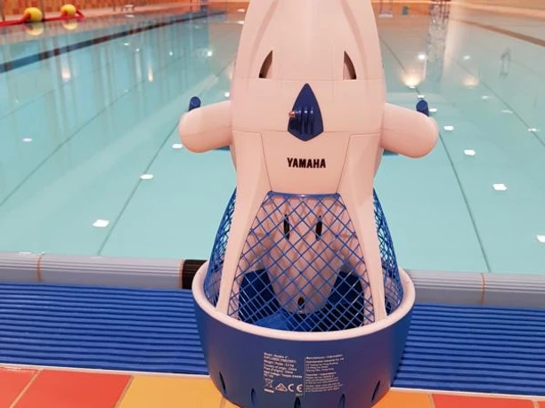 Bröltal-Bad Seascooter.jpg Ein Schwimmroboter der Marke Yamaha steht am Beckenrand in einem Hallenbad mit klarem Wasser.