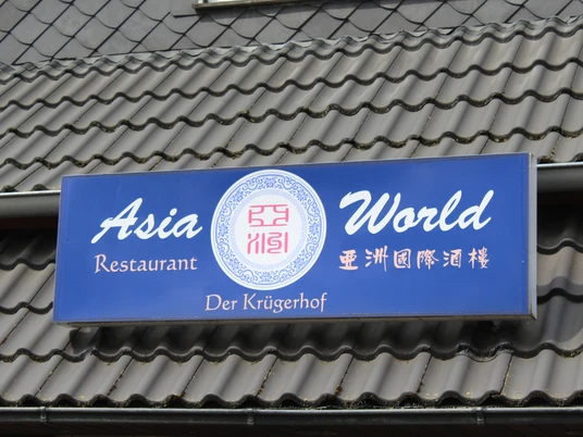 Blaues Schild mit weißer Schrift "Asia World" und chinesischen Zeichen vor einem Dach mit Dachziegeln.