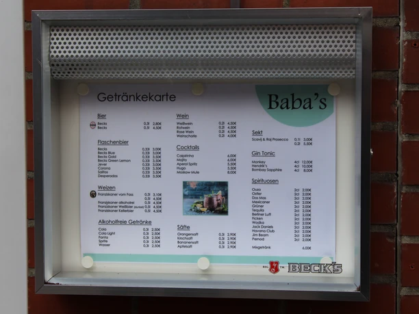 The drinks menu of Baba's Bistro, attached to a red brick wall, is presented.