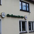 Jadehaus Das Jadehaus ist ein Lokal mit gelber Fassade, grüner Beschilderung und weißen Fensterrahmen.