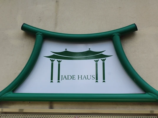 Jadehaus Das "Jadehaus" Schild mit grünem Rahmen zeigt ein stilisiertes Gebäude auf weißem Hintergrund.The "Jade House" sign with a green frame shows a stylized building on a white background."Jade House"-skiltet med grøn ramme viser en stiliseret bygning på en hvid baggrund.Het bord "Jade House" met een groen kader toont een gestileerd gebouw op een witte achtergrond.
