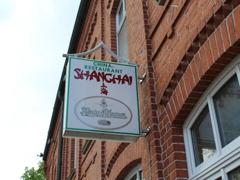 Shanghai Ein Schild des China-Restaurants "Shanghai" hängt an einer roten Backsteinfassade.