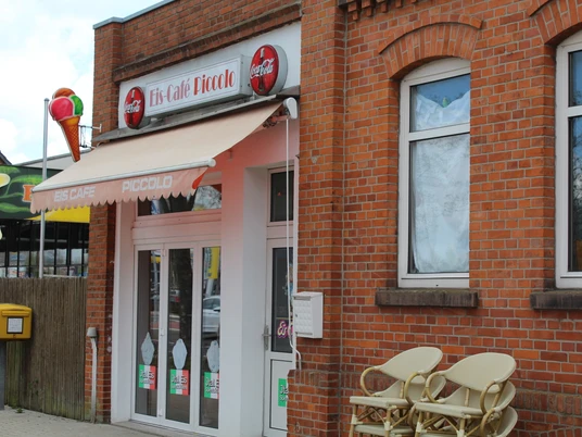 Eiscafé Picolo Eingang des Eiscafés Picolo mit roten Backsteinen und einem Sonnen-Markise an der Fassade.