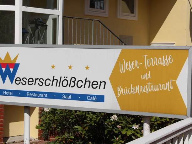 Sign for the Weserschlößchen with reference to the hotel, restaurant and bridge restaurant on a yellow background.