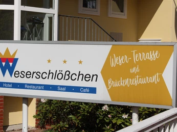 Brückenrestaurant Schild des Weserschlößchens mit Verweis auf Hotel, Restaurant und Brückenrestaurant auf gelbem Hintergrund.Sign for the Weserschlößchen with reference to the hotel, restaurant and bridge restaurant on a yellow background.Skilt til Weserschlößchen med henvisning til hotel, restaurant og bridgerestaurant på en gul baggrund.Bord voor het Weserschlößchen met verwijzing naar het hotel, restaurant en brugrestaurant op een gele achtergrond.