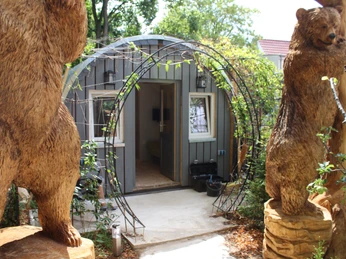 FeWo Bärenhöhle - KreativWerkstatt am Wall Ein kleines, hölzernes Ferienhäuschen mit Bärenstatuen am Eingang in einer grünen Umgebung.A small, wooden vacation cottage with bear statues at the entrance in a green setting.Et lille feriehus i træ med bjørnestatuer ved indgangen i grønne omgivelser.Een klein, houten vakantiehuisje met berenbeelden bij de ingang in een groene omgeving.