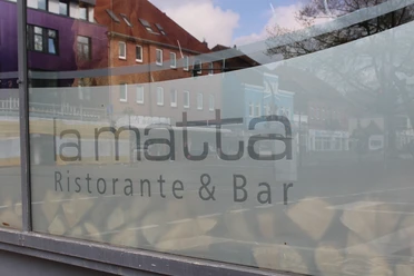 Das Foto zeigt das Restaurant "La Matta" in einer Straßenszene mit reflektierten Gebäuden im Fenster.