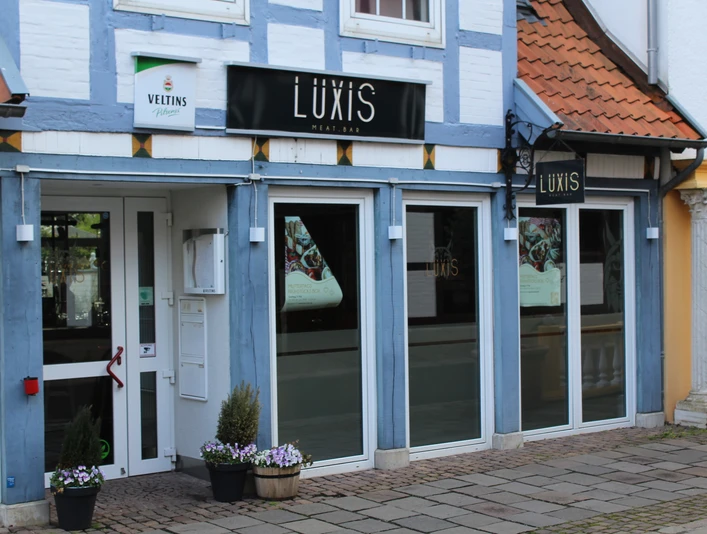 Luxis Meatbar Luxis Meatbar in einem Fachwerkhaus, mit blauen Holzbalken und einladenden, großen Fenstern.