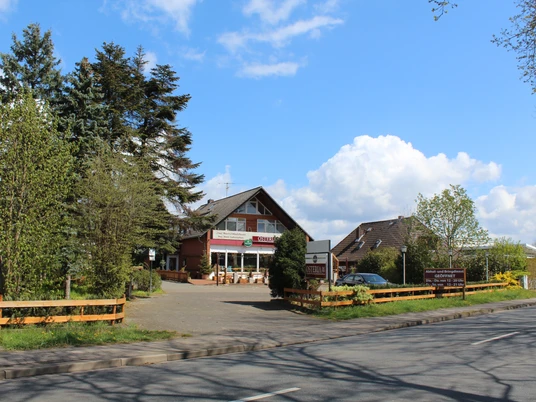 Osteria Ein Restaurant mit Terrasse, umgeben von Bäumen, an einer Landstraße unter blauem Himmel.A restaurant with a terrace, surrounded by trees, on a country road under a blue sky.En restaurant med terrasse, omgivet af træer, på en landevej under en blå himmel.Een restaurant met een terras, omringd door bomen, aan een landweggetje onder een blauwe hemel.