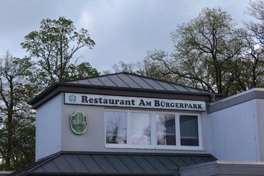 Restaurant am Bürgerpark Restaurant am Bürgerpark mit großer Fensterfront und grünen Bäumen im Hintergrund.
