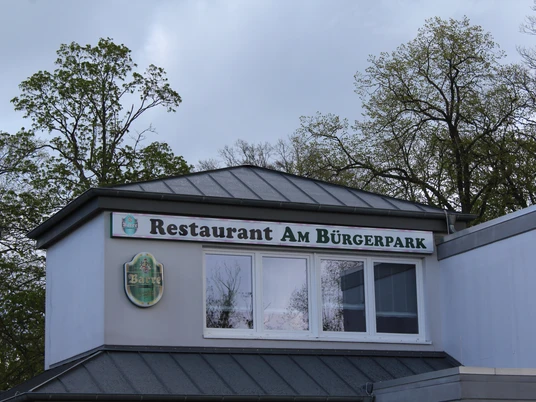 Restaurant am Bürgerpark Restaurant am Bürgerpark mit großer Fensterfront und grünen Bäumen im Hintergrund.Restaurant at Bürgerpark with a large window front and green trees in the background.Restaurant i Bürgerpark med stor vinduesfront og grønne træer i baggrunden.Restaurant in het Bürgerpark met een groot raam aan de voorkant en groene bomen op de achtergrond.