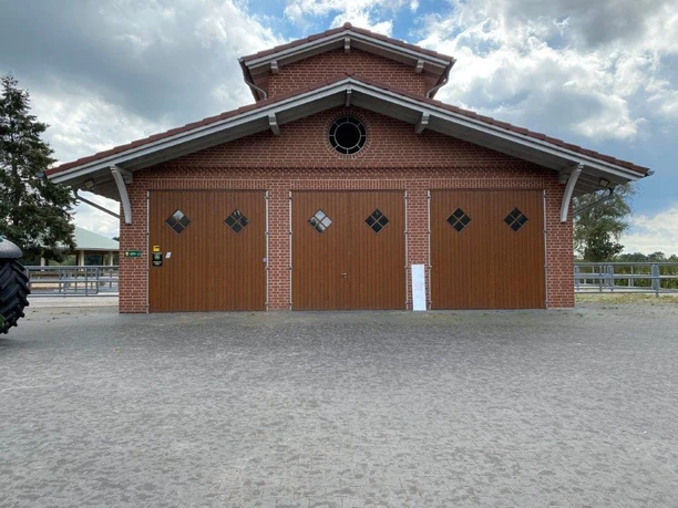 Hof Brentano Bawinkel Backsteingebäude mit drei Holztoren und kleinem Rundfenster, Teil eines Reit- und Landwirtschaftshofs.