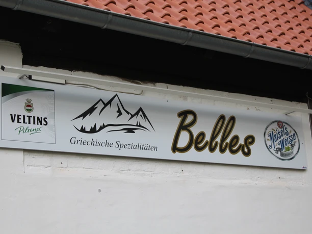 A sign with the words "Belles" and "Greek specialties" as well as logos of Veltins and Maisel's Weisse.