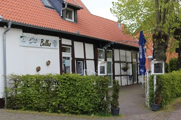Belles Historisches Fachwerkhaus mit angrenzendem Café und einladendem Garten, umgeben von grüner Hecke.