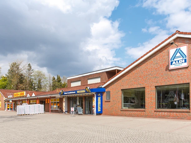 Wintering Meppenerstr._KHB_1725.jpg Backsteinbau mit Bäckerei Wintering und angrenzendem Supermarkt unter teils bewölktem Himmel