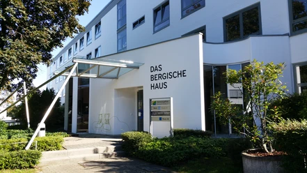 Das Bergische Haus.jpg Moderne Gebäudefront mit großem Schriftzug "Das Bergische Haus" und angrenzenden grünen Pflanzen.