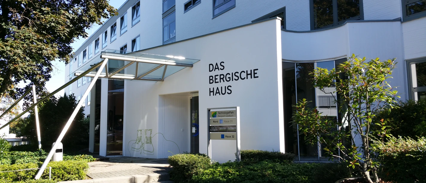 Das Bergische Haus.jpg Moderne Gebäudefront mit großem Schriftzug "Das Bergische Haus" und angrenzenden grünen Pflanzen.