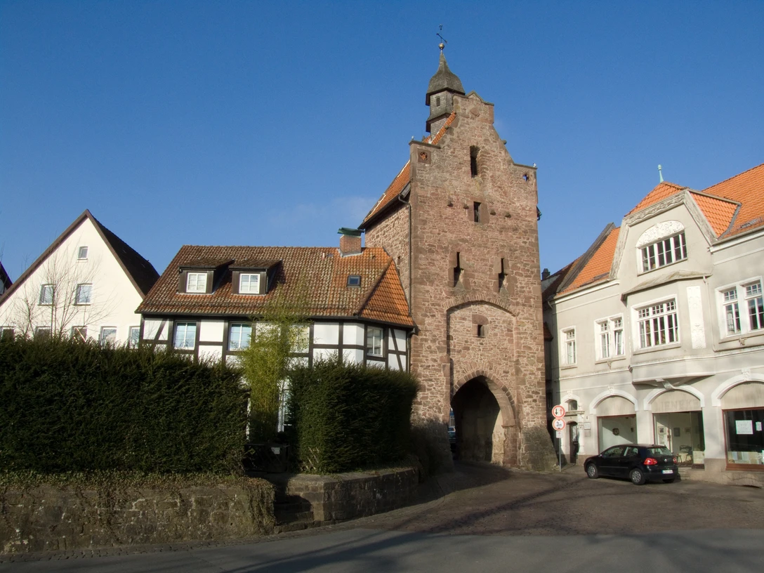 Niederntor_010-1.jpg Das historische Niederntor grenzt an Fachwerk- und Stadthäuser und steht unter klarem blauem Himmel.
