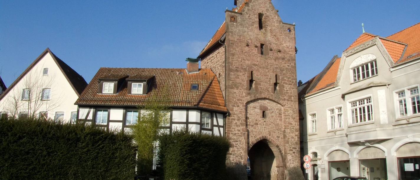 Niederntor_010-1.jpg Das historische Niederntor grenzt an Fachwerk- und Stadthäuser und steht unter klarem blauem Himmel.