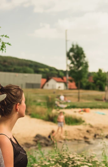 Emmerauenpark Lügde Zwei Personen stehen an einem Flussufer im Emmerauenpark Lügde, umgeben von grüner Natur.
