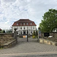 Gut Neuhof Petershagen Eingangstor mit Kopfsteinpflaster führt zu einem historischen, dreistöckigen Herrenhaus mit roten Dächern.
