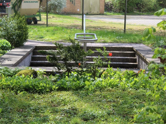 Kneippanlage Hoya Kneippanlage Hoya in einer grünen Umgebung mit Stufen und einer Metallstange zum Eintauchen im Wasser.