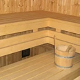 Helle Holzsauna mit mehreren Bänken und einem Holzeimer auf der unteren Bank in modernem Design.