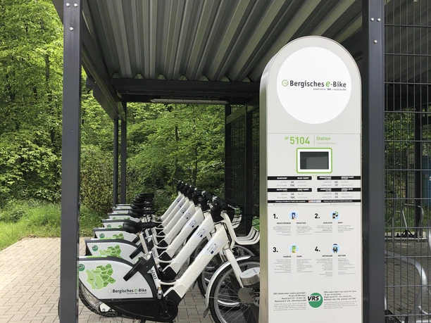 Mobilstation Bergisches e-Bike Odenthal-Altenberg Barrierefreie E-Bike-Verleihstation mit überdachten Rädern in grüner, naturreicher Umgebung.
